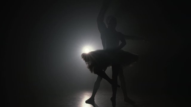 Professional ballet couple dancing in spotlights smoke on big stage. Beautiful young woman and man on floodlights background. Emotional duet performing choreographic art. Slow motion. 4k