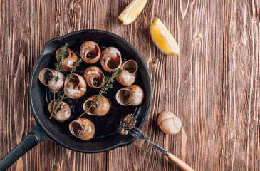 Bourgogne Escargot Snails with herbs butter in iron pan on rustic wooden background. Top view