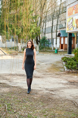 Photo of fashionable beautiful slender brunette girl posing striding in various poses in a city park in spring outdoors