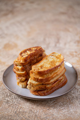 Fried croutons or egg toasts in a ceramic plate for morning coffee on an isolated light beige background. Stack of French toasts for breakfast