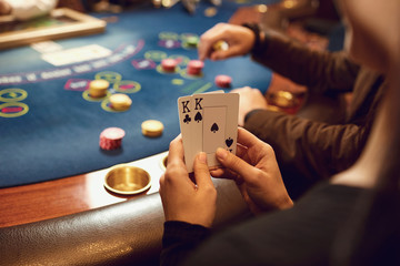 Close-up hands of a poker player checking cards in a casino.