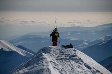 One man with ski equipment stands on top of snowy mountain.