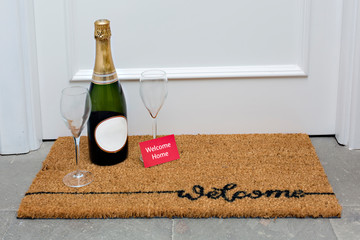 House entrance with carpet and champagne and card with the word welcome home.