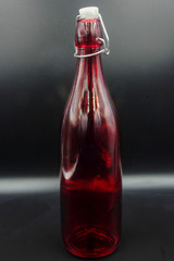 red glass bottle with stopper isolated on a black background