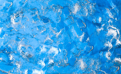 A piece of ice on a blue background. The structure and texture of the ice. Abstract pattern of frozen water.