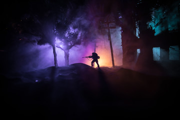 Naklejka na ściany i meble Army sniper with large caliber rifle standing in the fire and smoke. War Concept. Battle scene on war fog sky background, Fighting silhouettes Below Cloudy Skyline at night. City destroyed by war