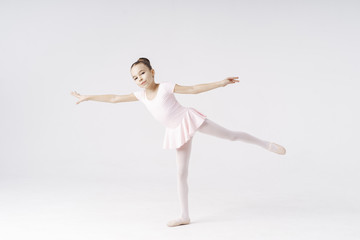 Fototapeta premium Adorable pre-teen ballerina dancing on white background