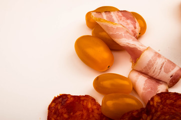 Slices of bacon and sausage and tomatoes on a white background. Close up.