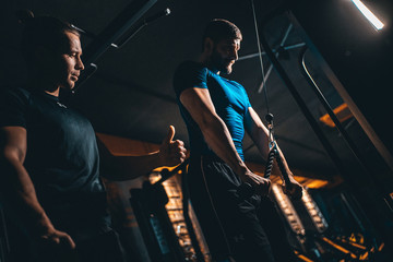 young man has workout with personal trainer in modern gym