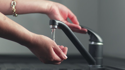 Hand is turning the hot running water flowing from tap on and off