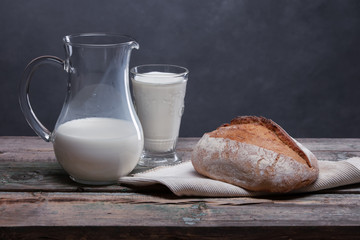 Still life: bread and milk on an old wooden table.