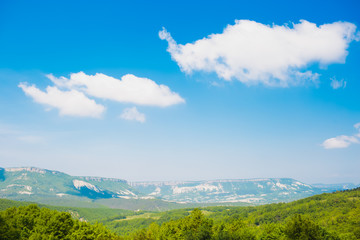 Landscape with mountains, sky and green grass.