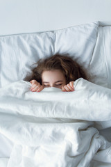 Stock photo - I stay at home awareness social media campaign and coronavirus prevention. Girl under the covers in her bed