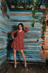 beautiful girl in a red dress stands against a blue wall