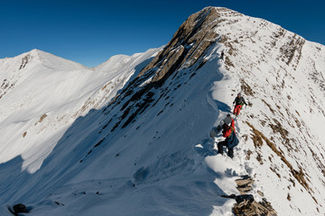Two athletes are preparing for the descent from snowy stone mountain.