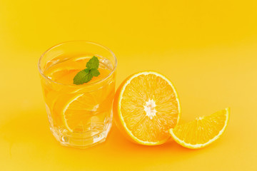 Detox Water with orange in a glass on an orange background