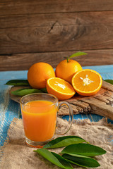 Fresh orange and a glass of orange juice on a wooden table background