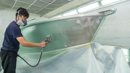 Repairman fixing by painting boat body and painting boat using spray gun