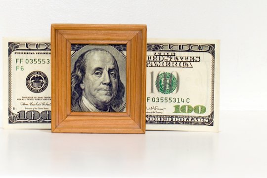 portrait of hundred dollar bill in wooden frame