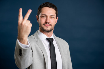 Portrait of business young handsome male showing number two