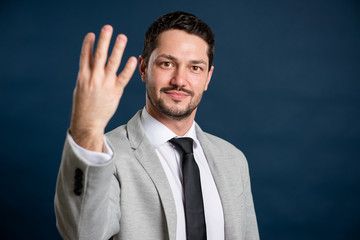 Portrait of business young handsome male showing number four