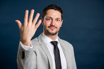 Portrait of business young handsome male showing number five