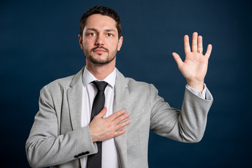 Portrait of business young handsome male making oath gesture