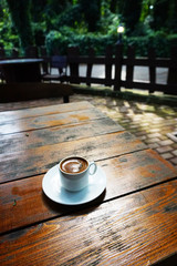 white mug with coffee on a wooden table in a coffee shop on the street
