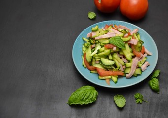 cucumber and ham salad next to Basil leaves and pepper on a