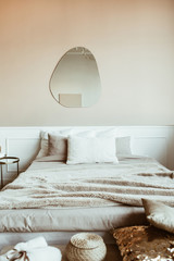 Stylish beige color bedroom with bed, linen, pillows, mirror, decorations. Modern classic interior design. © Floral Deco