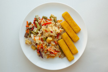 frying fish sticks in a pan. Homemade breakfast. Rice with vegetables and fried fish sticks.