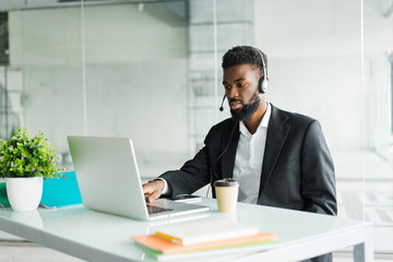 African american man customer support operator with hands-free headset working in the office.