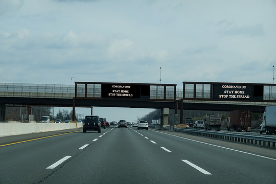 Electronic Information Sign Over A Busy Multi-lane Highway That Says Coronavirus Stay Home To Stop The Spread