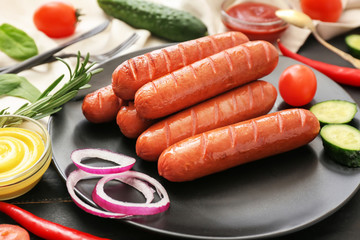 Plate with tasty grilled sausages and vegetables on table