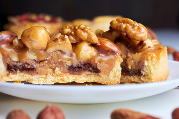 Сut mini tart cupcake mini tart cupcake with walnuts, almonds and hazelnuts on plate. Close up.