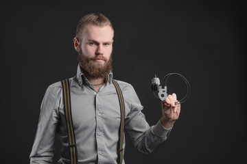 Handsome young man presents car parts on a gray background. The concept of sales and testing of goods