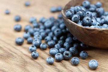 Freshly picked blueberries in bowl on wooden background. Selective focus. High resolution.