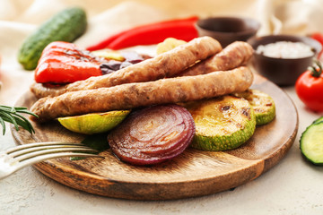 Plate with tasty grilled sausages and vegetables on table