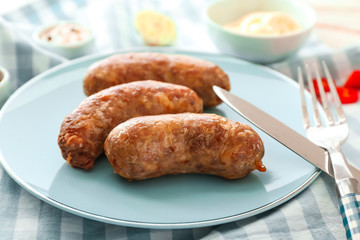 Plate with tasty grilled sausages on table