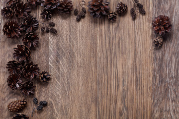 Christmas border design on the wooden background. Brown pinecones on old wood background top view. Christmas pine cone border with place for text. High resolution.