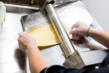 Chef rolling dough with a pasta machine. Pasta maker machine. 