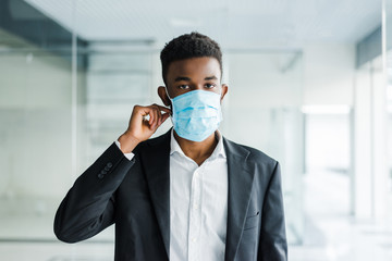 Young african man in medical mask on his face in office