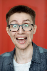 portrait of a cute guy with very bright facial expressions and emotions against a red wall