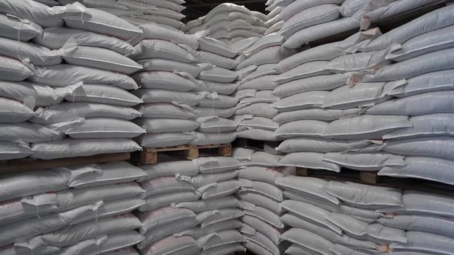 Production warehouse with folded white sacks of feed for rural animals. Agriculture and Resource Concept