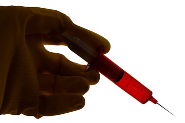 Syringe with red liquid held in a gloved hand. Close up backlit silhouette image isolated on white...