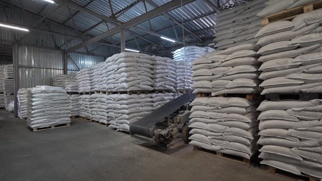 Production warehouse with folded white sacks of feed for rural animals. Agriculture and Resource Concept