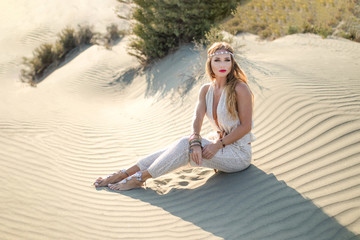 Beautiful caucasian female model dressed in oriental closes, belly dancer like, outdoor in a desert