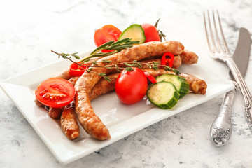 Plate with tasty grilled sausages and vegetables on white background
