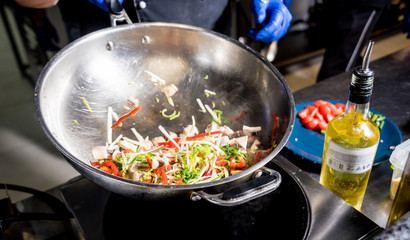 Chef cooking pasta with vegetables in pan. Italian style cuisine. Restaurant.