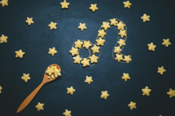 top view flat lay Leo horoscope sign made from crispy corn stars on a black background